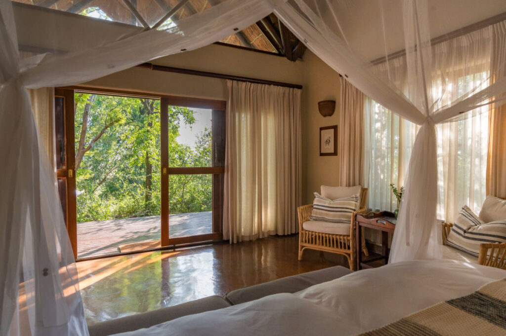 Spacious bedroom interior with glass doors opening to the bush